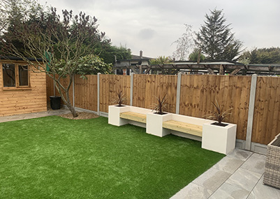 Fencing, bespoke log cabin, artificial lawn, rendered flowerbeds with built in seating, porcelain paving and pathway Chigwell essex