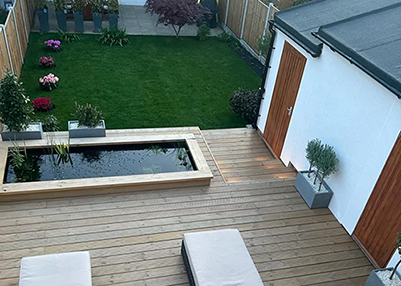 Porcelain patio, fencing, decking, pond, rendered extended outbuilding in Romford