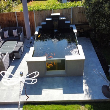 raised koi pond with three viewing windows, porcelain patio around, landscaping essex